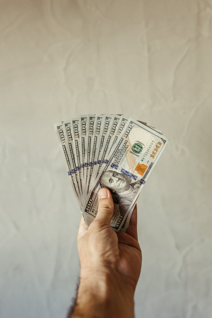 Mastering the First Impression: Your intriguing post title goes here A hand displays a fan of US hundred dollar bills against a plain background.