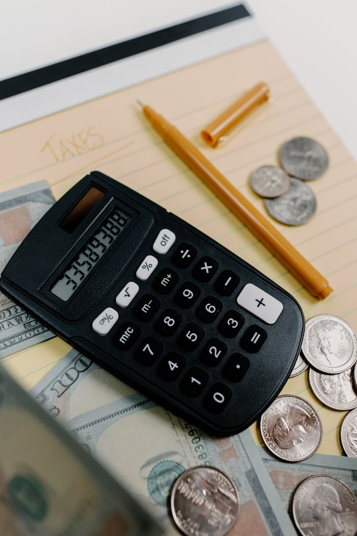 trusted-partner Close-up of a calculator, cash, and coins on a desk with a notepad and pen for financial planning.